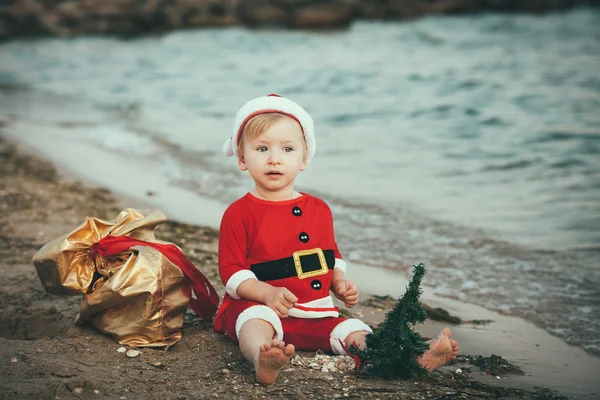 Baby Santa Claus op een zandstrand — Stockfoto