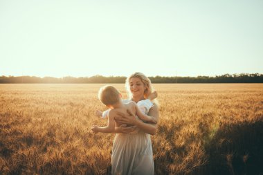 Anne ve oğlu gölün alan açık havada doğanın keyfini eğleniyor. Siluetleri güneşli gökyüzü üzerinde. Sıcak filtre ve film etkisi