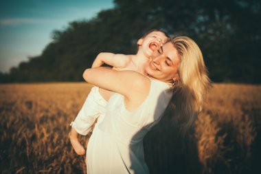 Anne ve oğlu gölün alan açık havada doğanın keyfini eğleniyor. Siluetleri güneşli gökyüzü üzerinde. Sıcak filtre ve film etkisi
