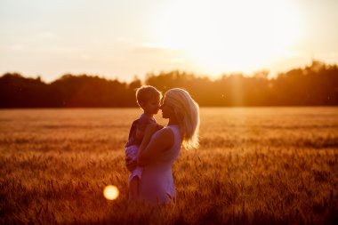 Anne ve oğlu gölün alan açık havada doğanın keyfini eğleniyor. Siluetleri güneşli gökyüzü üzerinde. Sıcak filtre ve film etkisi