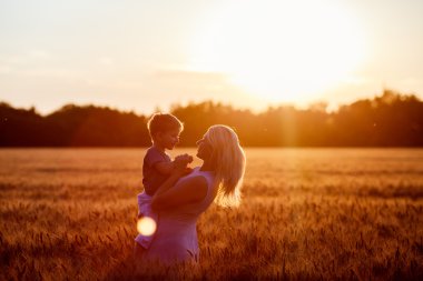 Anne ve oğlu gölün alan açık havada doğanın keyfini eğleniyor. Siluetleri güneşli gökyüzü üzerinde. Sıcak filtre ve film etkisi