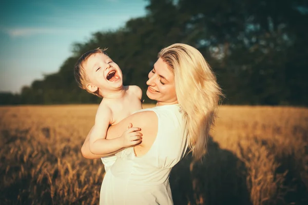 Mom and son having fun by the lake, field outdoors enjoying nature. Silhouettes on sunny sky. Warm filter and film effect — Stock Photo, Image