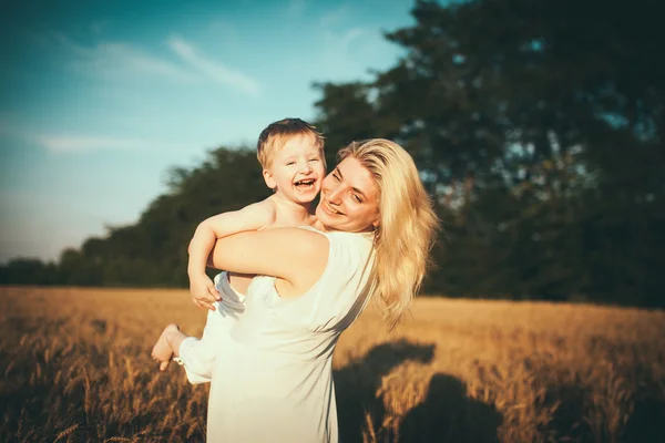 Mamá e hijo divirtiéndose junto al lago, campo al aire libre disfrutando de la naturaleza. Siluetas en el cielo soleado. Filtro caliente y efecto de película —  Fotos de Stock