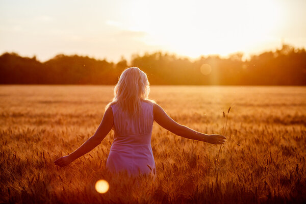 "Beauty Romantic Girl Outdoors". Девочка-подросток в казуальном платье на поле при солнечном свете. Длинные волосы. Осень. Светящееся солнце, солнышко. Подсветка. Тонированные в теплых тонах
