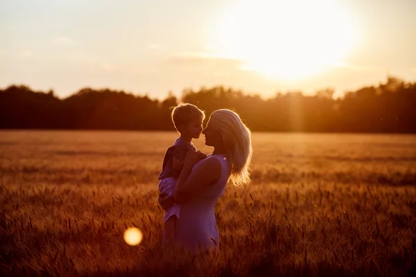 Mamma och son ha roligt vid sjön, fältet utomhus njuter av naturen. Silhuetter på solig himmel. Varmt filter och film effekt — Stockfoto