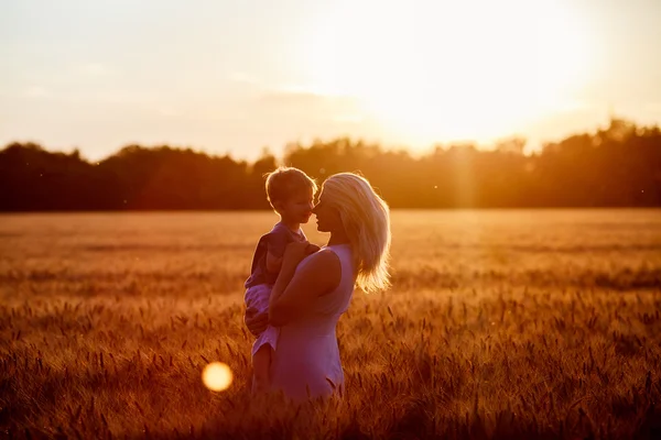 Mamá e hijo divirtiéndose junto al lago, campo al aire libre disfrutando de la naturaleza. Siluetas en el cielo soleado. Filtro caliente y efecto de película —  Fotos de Stock