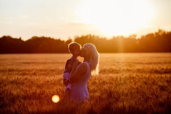 Mamma och son ha roligt vid sjön, fältet utomhus njuter av naturen. Silhuetter på solig himmel. Varmt filter och film effekt — Stockfoto