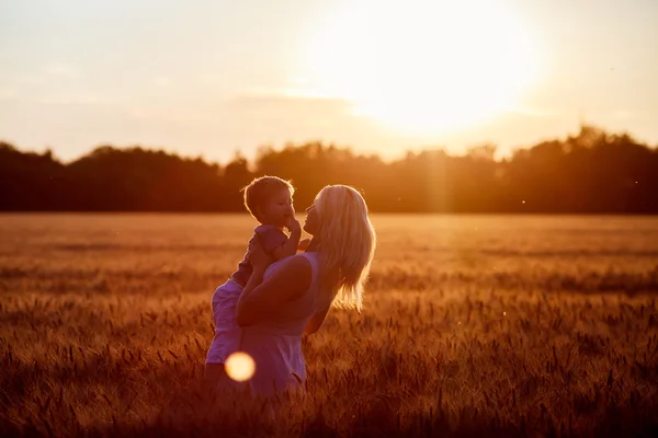 Mamma och son ha roligt vid sjön, fältet utomhus njuter av naturen. Silhuetter på solig himmel. Varmt filter och film effekt — Stockfoto