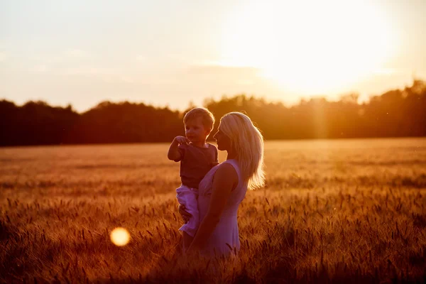 Mamá e hijo divirtiéndose junto al lago, campo al aire libre disfrutando de la naturaleza. Siluetas en el cielo soleado. Filtro caliente y efecto de película —  Fotos de Stock