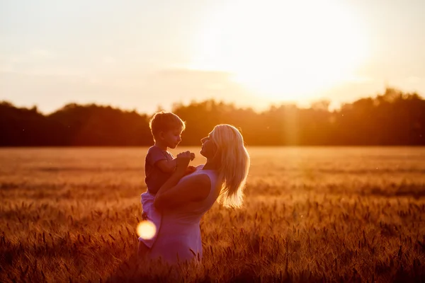 Mom and son having fun by the lake, field outdoors enjoying nature. Silhouettes on sunny sky. Warm filter and film effect — Stock Photo, Image