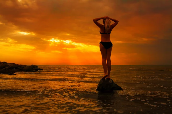 Silueta de una mujer sensual al amanecer en la playa —  Fotos de Stock