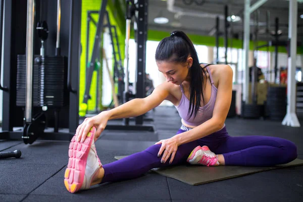 Du sport. Femme au gymnase faisant des exercices d'étirement et souriant sur le sol Images De Stock Libres De Droits