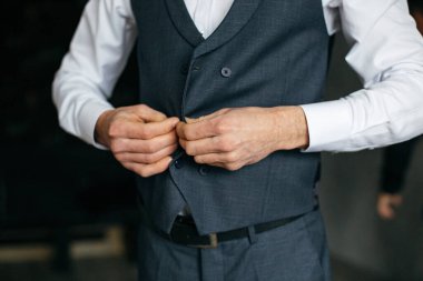 Gri takım elbiseli neşeli genç bir adam cekete dokunuyor.