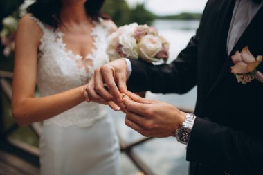 Nişan yüzükleri. Evli çiftler nikah töreninde alyanslarını takarlar. Damat, sevgili karısının parmağına yüzük taktı. Düğün detaylarını düşün. Mutlu bir aile. Birlikte.