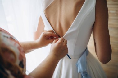 Düğün sabahı. Gelinlik giymiş gelinin yan görüntüsü. Nedimeler gelini düğün gününe hazırlıyorlar..