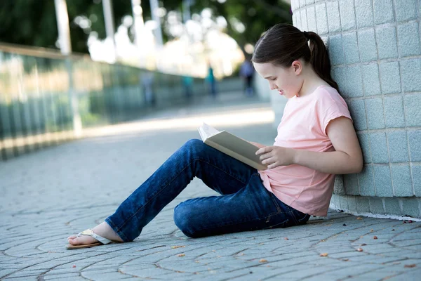 Ragazza all'aperto leggendo un libro bianco whist studiare o rilassarsi . — Foto Stock