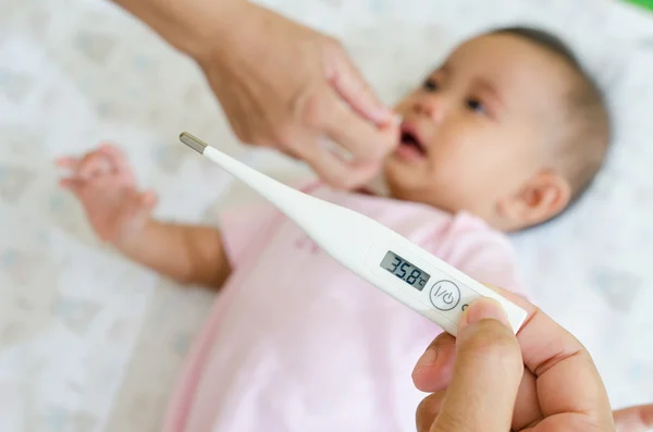 Measuring Asian baby temperature with digital thermometer