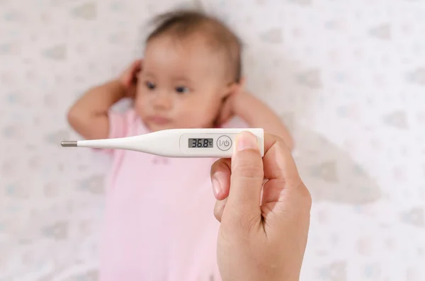 Pomiar temperatury Azjatki baby z termometr cyfrowy — Zdjęcie stockowe