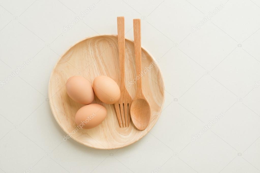 Fresh raw eggs isolated on wood dish over light background