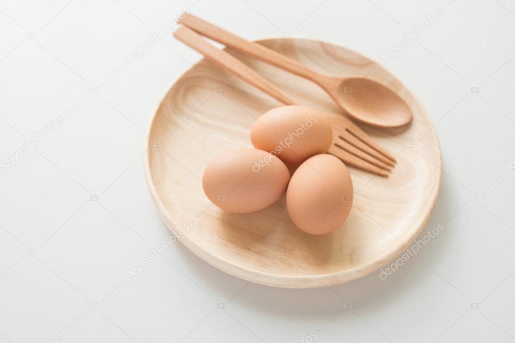 Fresh raw eggs isolated on wood dish over light background