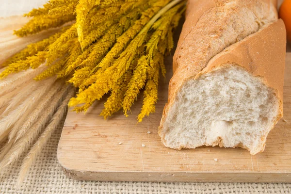 Baguettes de pan francés sobre tabla de pan y naranjas de mandarina — Foto de Stock