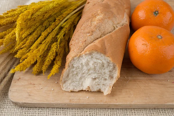 Baguette di pane francese su tagliere e arance mandarine — Foto Stock