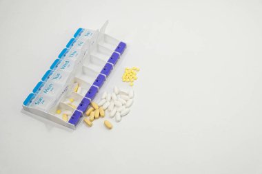 Haftalık ilaç planlayıcısı. Önündeki bazı malzemeler ilaç kutusuna yükleniyor.