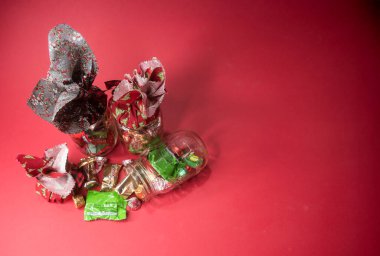 Üç Noel hediyesi, biri açık ve dökülmüş, kırmızı arka planda. Yukarıdan bakıldığında.