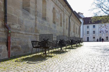 Cavid-19 'daki kafe restoranı Almanya' nın tarihi şehrinde boş masa ve sandalyeleri kilitleyin.