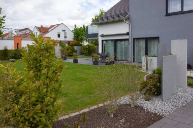 Almanya 'da baharda yeşil ve taş duvar cepheleri olan modern bahçe evleri.