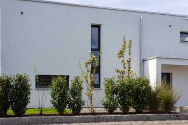 Almanya 'da baharda yeşil ve taş duvar cepheleri olan modern bahçe evleri.