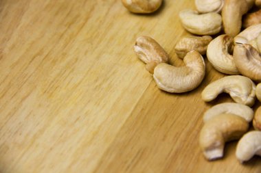 Sağ tarafta kaju fıstığı var. Hafif ahşap arka plana yerleştirilmiş.