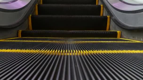 Vista en bucle de ángulo bajo de escaleras mecánicas modernas. Mecanismo de ascensor automatizado. Línea amarilla en escalera iluminada con luz púrpura. Escalera de maquinaria vacía futurista moviéndose recta — Vídeo de stock