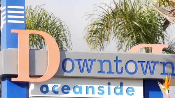 Oceanside tablicy znamionowej i palm. Oside jest popularny amerykański kurort turystyczny, Pacyfik ocean zachodnie wybrzeże, San Diego County, Kalifornia USA. Nazwa miasta wakacji i turystyki na wybrzeżu — Wideo stockowe