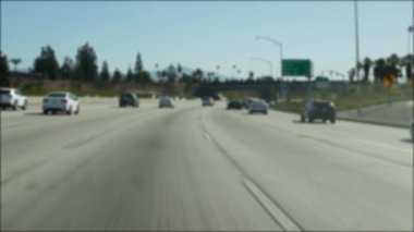 Los Angeles, Kaliforniya 'da şehirlerarası otobanda araba sürüyorum. Yoğun otoyoldaki arabanın cam ön camından odaklanmış görüntüsü. Bulanık banliyö yolu. Kamera Los Angeles 'ta.