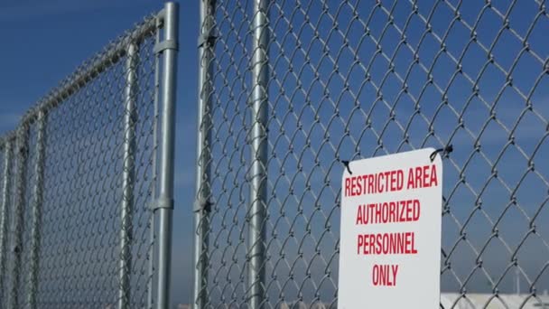 Restricted area, authorized personnel only sign in USA. Red letters, keep off warning on metal fence, United States border symbol. No trespassing notice means violators will be prosecuted by US law — Stock Video