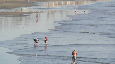Oceanside, California USA - 11 Şubat 2020: Yerli halk, Pasifik Okyanusu kıyısında, iskeleden sahile doğru yürüyor. Deniz suyu dalgaları, sahil kumu. Deniz kıyısındaki tatil beldesi. Rıhtım Alanı.