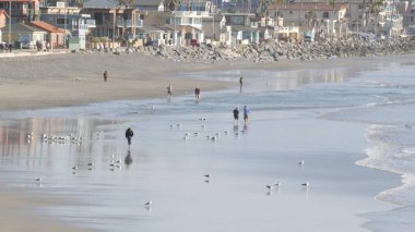 Oceanside, California USA - 11 Şubat 2020: Yerli halk, Pasifik Okyanusu kıyısında, iskeleden sahile doğru yürüyor. Deniz suyu dalgaları, sahil kumu. Deniz kıyısındaki tatil beldesi. Rıhtım Alanı.