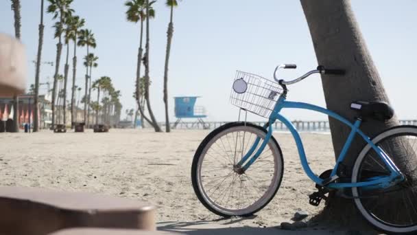 Bicicleta de cruzador de bicicleta por praia oceânica, costa da Califórnia EUA. Ciclo de verão, cabana salva-vidas e palmeira — Vídeo de Stock