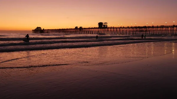 Silueta de surfista, puesta de sol pacífica en la playa del océano. La gente disfruta del surf. Oceanside, California EE.UU. — Foto de Stock