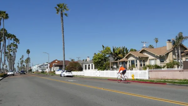 Persona montando en bicicleta, palmeras y personas en el complejo costero pacífico Oceanside, California, EE.UU.. —  Fotos de Stock
