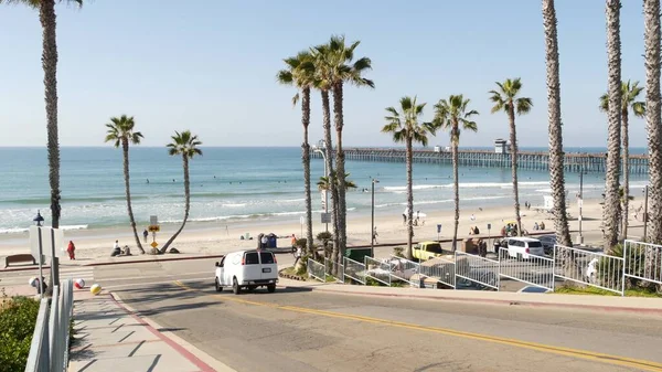 Bicyclist man, people in ocean beach waterfront resort, palms. Beachfront road street California USA — Stock Photo, Image