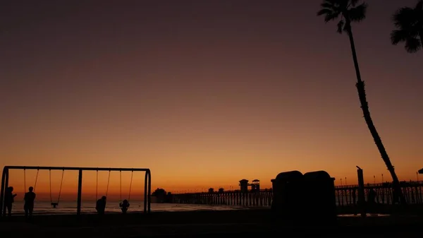 Waterfront playground. Children play, sunset ocean beach. Beachfront recreation area. California USA — Stock Photo, Image