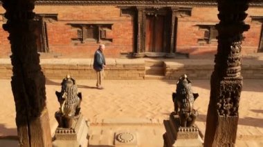 BHAKTAPUR, KATHMANDU, NEPAL - 18 Ekim 2018 Doğu antik kentinde deprem sonrası yaya trafiği. Ulusal giysili yerel newar insanları tapınağın yakınındaki sokaklara gidiyorlar..