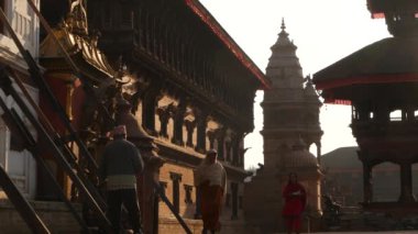 BHAKTAPUR, KATHMANDU, NEPAL - 18 Ekim 2018 Doğu antik kentinde deprem sonrası yaya trafiği. Ulusal giysili yerel newar insanları tapınağın yakınındaki sokaklara gidiyorlar..