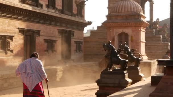 Bhaktapur Kathmandu Nepal October 2018地震後の東洋古代都市の歩行者の毎日の交通 寺院の近くの通りに行く民族衣装を着た地元の新参者 — ストック動画