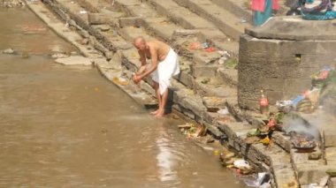 KATHMANDU, NEPAL - 8 Ekim 2018 Sikha Brahman 'la dua ederek yas ayinleri yapıyor. Tonsure Hindu geleneği. Puja. Pashupatinath Tapınağı. Yas tutanlar, hacılar, ghatlarda yakma töreni.