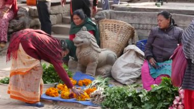 BHAKTAPUR, KATHMANDU, NEPAL - 18 Ekim 2018 Asyalılar ulusal giysiler ve sabah sebze tapınağı pazarında ürün satıyorlar. Günlük ticaret hayatı, depremden sonra antik doğu şehri.