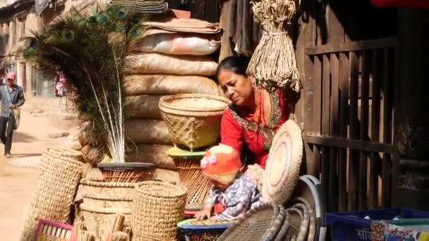 Bhaktapur Nepal October 2018家の庭に子供を持つ女性 赤ちゃんと民族の女性は 明るい日差しの中で販売するためのウィカーバスケットがたくさん 東日本大震災後の古代都市 — ストック動画