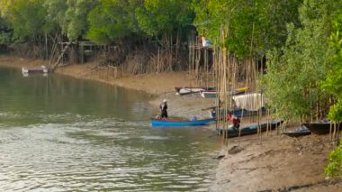 Günün sonunda iki balıkçı Mangrove Ormanı 'ndaki köyün kıyısında konuşuyor..